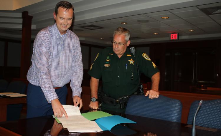 Jay Swisher, left, who will be sworn-in as the interim clerk of courts in a private ceremony today, reviews paperwork with Sgt. Mike Sweat of the Columbia County Sheriff’s Office Judicial Division. (TONY BRITT/Lake City Reporter)