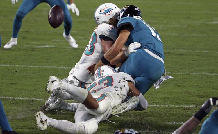 Jacksonville Jaguars quarterback Gardner Minshew, right, fumbles the ball as he is hit by Miami Dolphins outside linebacker Andrew Van Ginkel, left, and middle linebacker Kyle Van Noy during Thursday's game in Jacksonville. (STEPHEN B. MORTON/Associated Press)