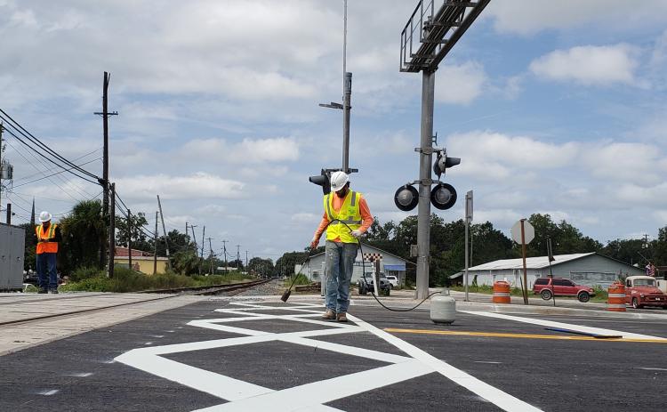 Crews finish work on the dynamic envelopes — giant connecting white X’s — at the rail crossing on U.S. Highway 129 (Ohio Avenue) in downtown Live Oak. The crossing reopened Monday night after being closed for two weeks for the improvements, which are part of the Florida Department of Transportation’s Operation STRIDE. (COURTESY FDOT)