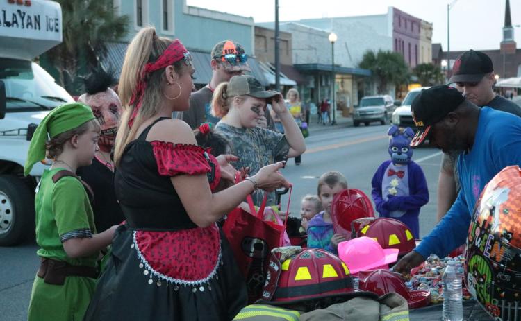 Trick-or-treaters receive candy from the Live Oak Fire Department’s booth at the Candy Carnival in downtown Live Oak last year. This year the city’s Community Redevelopment Agency is helping to sponsor a drive-in event at Heritage Park and Gardens. (SUWANNEE DEMOCRAT)