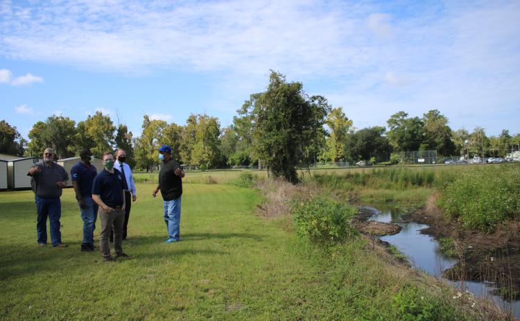 Thomas Henry (clockwise from left), Lake City Public Works Department Director; Leroy Marshall, Suwannee River Water Management District Chief Professional Engineer; Tim Beach, Suwannee River Water Management District Environmental Scientist II; and Joe Helfenberger, city manager, talk to Adee Farmer about drainage issues near a canal near Richardson Community Center. (TONY BRITT/Lake City Reporter)