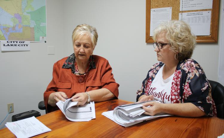 Liz P. Horne (left), Columbia County supervisor of elections and Tomi Brown, Columbia County deputy supervisor of elections, look through stacks of voter registrations Monday, the final day to register.  (TONY BRITT/Lake City Reporter)