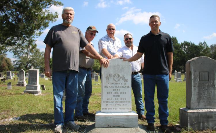 James Smith (from left), stands with Al Williams, Chuck Denmark, Jordan Thrasher and Derek Smith around the headstone of Thomas C. Strange, a Columbia County resident who was reportedly the first Confederate soldier killed in Florida during the Civil War. The Smiths are descendants of Strange, while Williams, Denmark and Thrasher serve as trustees for the cemetery. (TONY BRITT/Lake City Reporter)