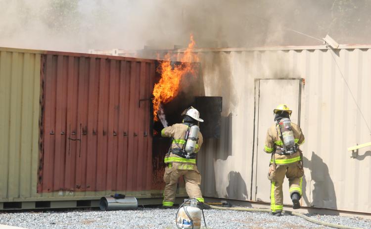 A firefighter uses a hose to douse flames coming from a window during a training session Friday. (TONY BRITT/Lake City Reporter)