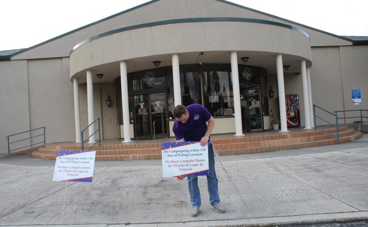 Kent Banner, an elections office staff member, prepares for early voting by adding signs in front of the supervisor of elections office. (TONY BRITT/Lake City Reporter)