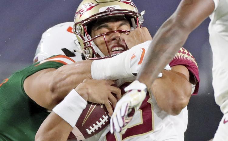 Florida State quarterback Jordan Travis (13) is tackled by a Miami player on Sept. 26 in Miami Gardens. (AL DIAZ/Miami Herald via AP)