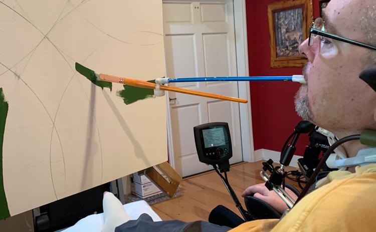 Peter Herrick, a tetraplegic combat veteran from Fort White, paints using a modified paintbursh and a rotating easel. He is the November featured artist at the Gateway Art Gallery. (COURTESY)