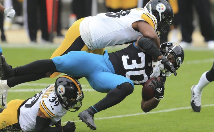 Jacksonville Jaguars running back James Robinson (30) is brought down by Pittsburgh Steelers linebacker Vince Williams, top, and safety Minkah Fitzpatrick (39) on Nov. 22 in Jacksonville. (MATT STAMEY/Associated Press)