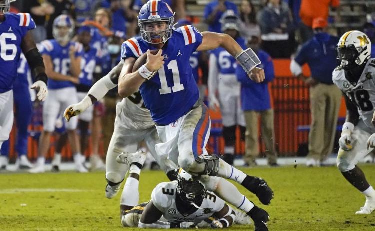 Florida quarterback Kyle Trask (11) runs past Missouri's Martez Manuel (3) and linebacker Nick Bolton, back left, this past Saturday in Gainesville. (JOHN RAOUX/Associated Press)