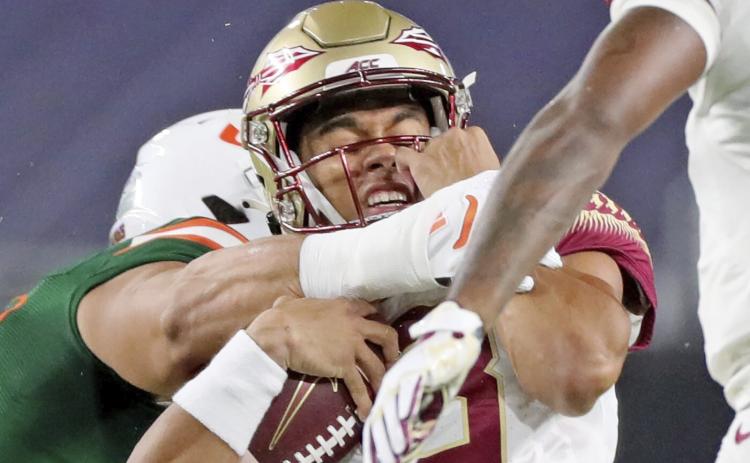 Florida State quarterback Jordan Travis (13) is tackled by a Miami player on Sept. 26 in Miami Gardens. (AL DIAZ/Miami Herald via AP)