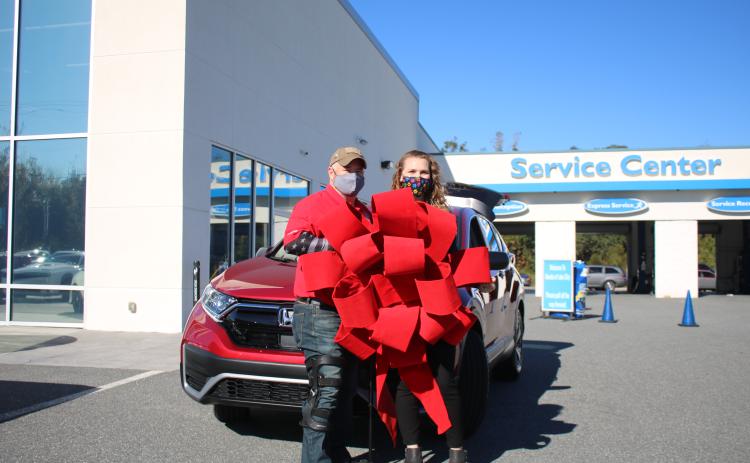 Veteran Jesse Todd, a retired U.S. Army Staff Sergeant who was wounded in Afghanistan, stands with his wife Julia Todd, as the two hold a red ribbon in front of their new 2020 Honda CR-V. Todd, the recipient of a Purple Heart, was given the payment-free vehicle through the Military Warriors Support Foundation’s Transportation4Heroes program Tuesday afternoon at Honda of Lake City. (TONY BRITT/Lake City Reporter)