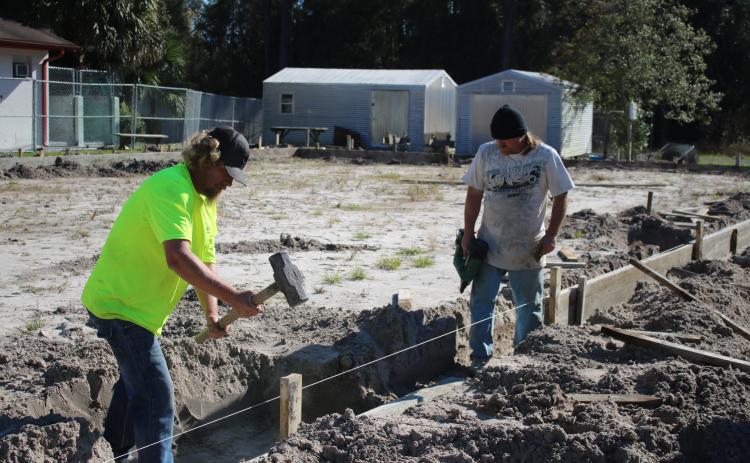 William Glover (left) and Kerry DeYoung put stakes in the ground Wednesday afternoon while doing preparation work for the James Montgomery Animal Wellness Center at the Lake City-Columbia County Humane Society. (TONY BRITT/Lake City Reporter)