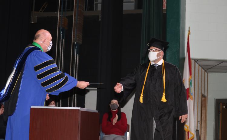 Lawrence Barrett (left), Florida Gateway College President, gives Kevin Doorman his water services bachelors degree during commencement exercises Thursday evening at the college. (TONY BRITT/Lake City Reporter)