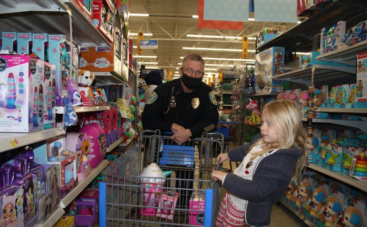 Ryleigh Harden gets a ride on a shopping cart from Lake City Police Department Lt. Andy Miles while Christmas shopping during the Shop with a Cop program Wednesday morning at Walmart. Thirty local children were able to go Christmas shopping with LCPD officers during the event. (TONY BRITT/Lake City Reporter)