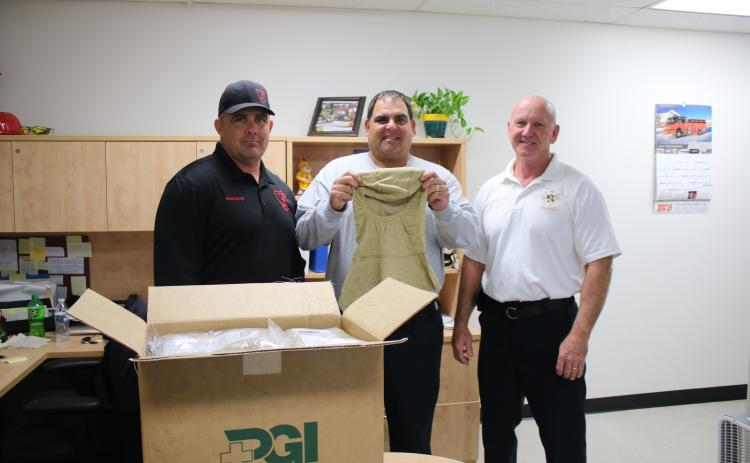 Billy Brideson (from left), owner of 3rd Alarm Public Safety Training, stands with Tad Cervantes, CCFR assistant chief and Jeff Crawford, CCFR  Chief, as they a show a new hood county firefighters will receive. The Nomex particulate hoods increase firefighter safety against carcinogens. The county fire department recently purchased 54 of the hoods with funds raised through a 3rd Alarm training session. (TONY BRITT/Lake City Reporter)