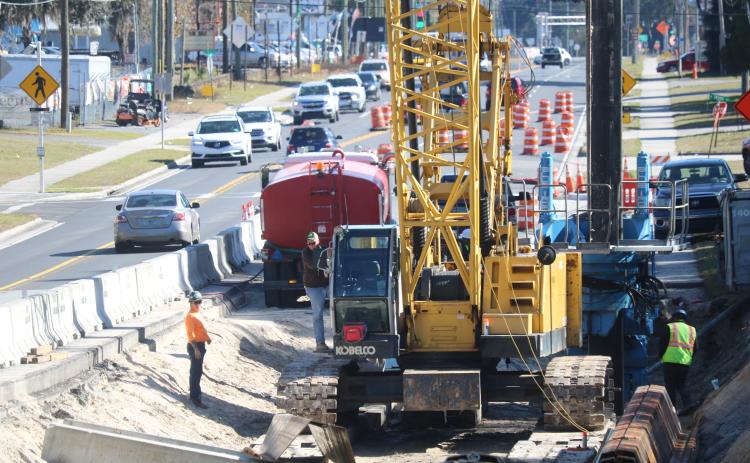 Construction workers use an excavator and other heavy machinery Tuesday afternoon while working on U.S. Highway 90 during a sheet piling operation to stabilize the roadway. (TONY BRITT/Lake City Reporter)