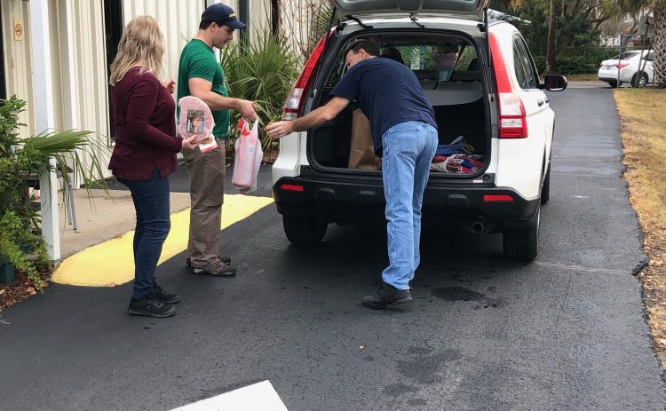 Sadie House (from left), Christian Service Center assistant director, Ben Walker and Mike House load goods into a Christian Service Center client’s vehicle Monday. (COURTESY)