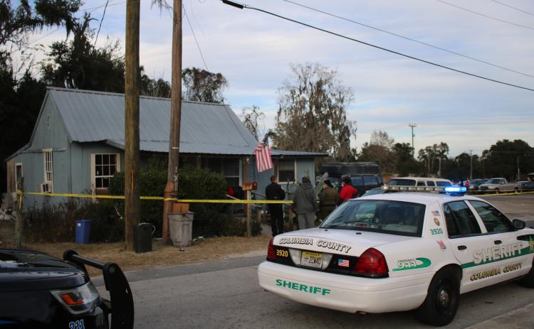 Lake City Police Officer Lt. Keith Heston (left) talks to a group of unidentified people at 179 NW Escambia Street, near the intersection of NE Calhoun Street, where a shooting occurred Wednesday afternoon. (TONY BRITT/Lake City Reporter)