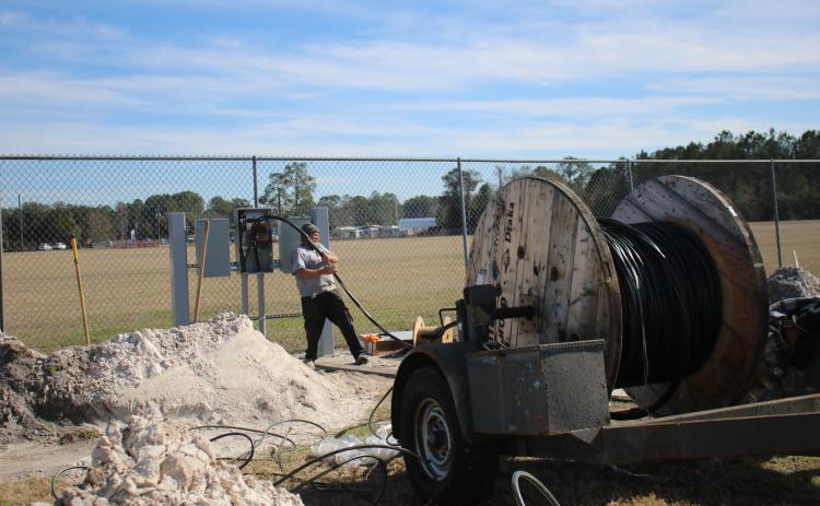 Jay Lambert pulls wire from a large spool while working on upgrades at the Florida Gateway Fairgrounds Rodeo Arena. The facility is adding more RV campsites for events. (TONY BRITT/Lake City Reporter)
