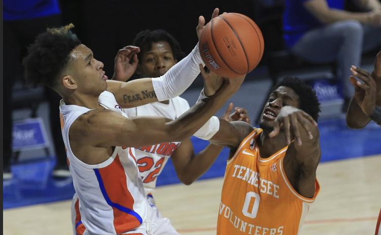 Florida guard Tre Mann (1) and Tennessee guard Davonte Gaines (0) compete for a rebound on Tuesday in Gainesville. (MATT STAMEY/Associated Press)