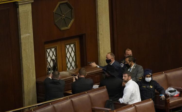 U.S. Capitol police officers point their guns at a door that was vandalized in the House Chamber during a joint session of Congress on Wednesday in Washington, D.C. (DREW ANGERER/Getty Images/TNS)