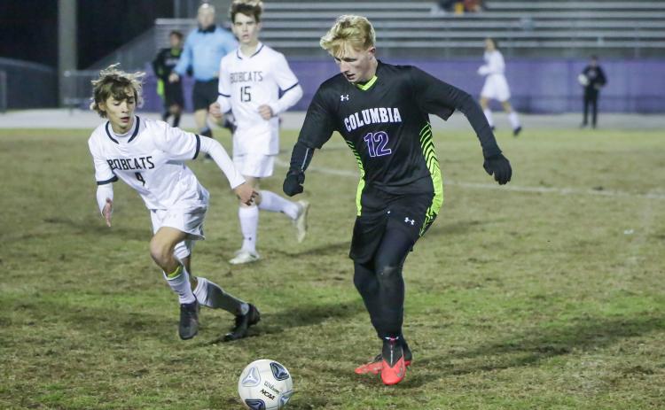 Columbia’s Zack Strickland dribbles up the field while Buchholz’s Riley Smith gives chase during Wednesday’s District 2-6A semifinals. (BRENT KUYKENDALL/Lake City Reporter)