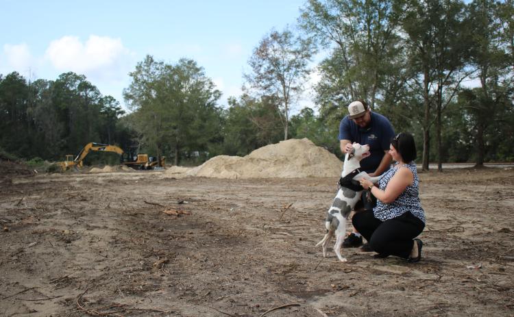 Jordan Regar, Lake City Humane Society Community Development manager, and Damen Modlinski, a humane society adoptions counselor, walk Misty, a Staffordshire Bull Terrier, on property that will serve as the humane society’s dog park. Misty, an 18-month-old dog, was found at the corner to two intersections tied to a post, is available to foster for possible adoption. (TONY BRITT/Lake City Reporter)