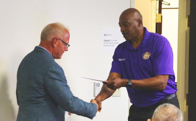 Gary Wilson (from left) receives a thank-you note and handshake from Columbia track & field coach Lawrence Davis during Thursday’s meeting. (MORGAN MCMULLEN/Lake City Reporter)
