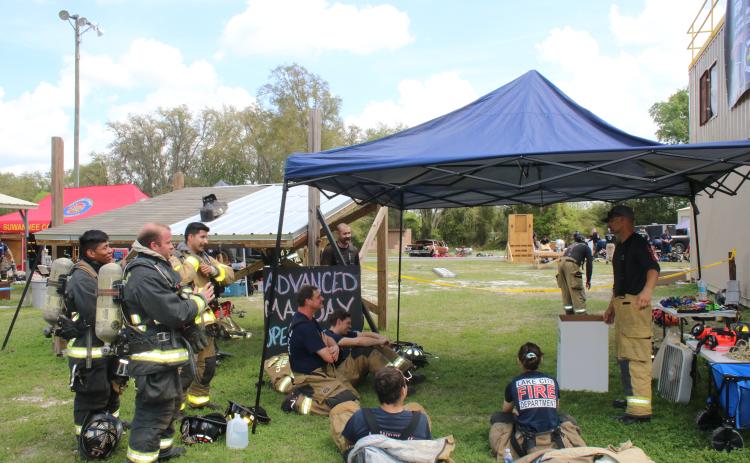 Firefighters adjust their gear as they listen to a Third Alarm Public Safety Training instructor present tips on firefighter survival. (TONY BRITT/Lake City Reporter)