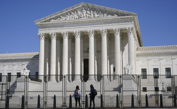 People view the Supreme Court building from behind security fencing on Capitol Hill on March 21 in Washington after portions of an outer perimeter of fencing were removed overnight to allow public access. A Supreme Court case being argued this week amid March Madness could erode the difference between elite college athletes and professional sports stars. (AP FILE PHOTO)