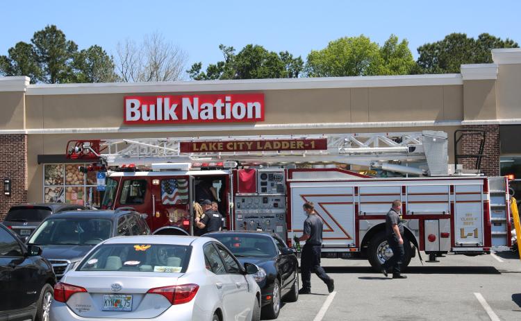 Officers walk with a man after they talked him down from the roof of Bulk Nation on Thursday afternoon. The man had been yelling and throwing clothes off the top of the building. (TONY BRITT/Lake City Reporter)