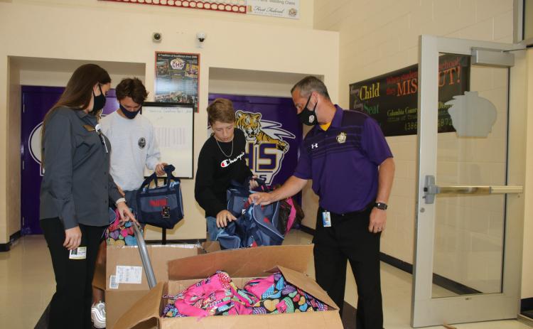 Stacy Albritton, DCF supervisor of Child Investigations (from left), stands with A.J. Kihei, Columbia High School student body president, Elijah Dockery, chairman of the Hope Bags Drive and Trey Hosford, Columbia High School principal, as they look at Hope Bags that will be donated to local children in foster care. (TONY BRITT/Lake City Reporter)