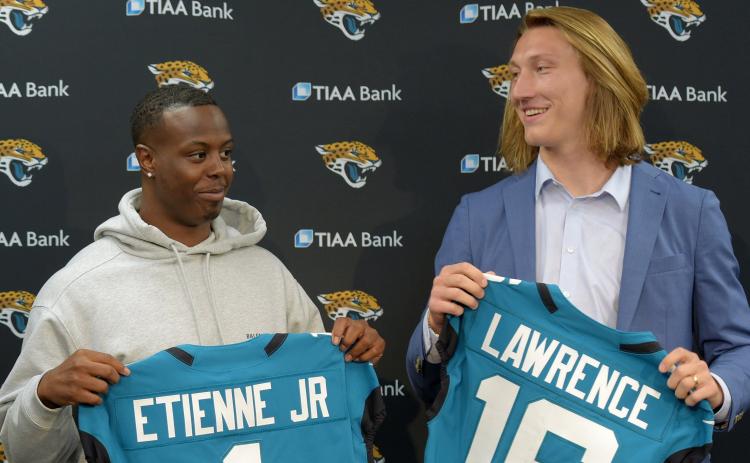 Former Clemson teammates and now Jaguars teammates running back Travis Etienne, left, and quarterback Trevor Lawrence pose with their new teal jerseys prior to an introductory press conference on April 30 at TIAA Bank Field in Jacksonville. (BOB SELF/TNS)