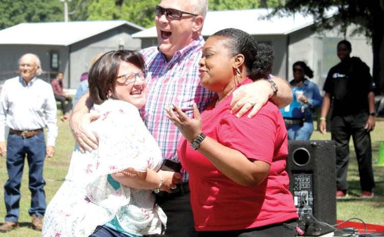 Karen Terry (from left) hugs Burney Ratliff, the 2022 Columbia County Schools Teacher of the Year, as he stands next to Pathways Academy Principal Makeba Murphy. Ratliff, a social studies teacher at Pathways Academy, was given a new car Friday morning for being awarded the 2022 Columbia County Schools Teacher of the Year. (TONY BRITT/Lake City Reporter)