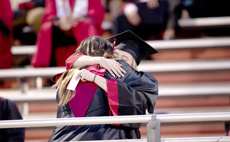 A Fort White High School graduate hugs one of her teachers Friday night during the commencement ceremony. (JACOB PRICE/Special to the Reporter)