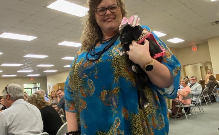 Renee Williams, a model for the Lake City-Columbia County Humane Society inaugural fashion show, holds a puppy as she models clothing and accessories from the agency’s thrift store. (COURTESY)