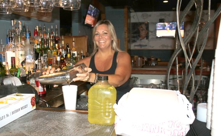 Kelly Cason, a bartender at Phish Tales, prepares a to-go order which includes alcohol at the restaurant Thursday afternoon. (TONY BRITT/Lake City Reporter)