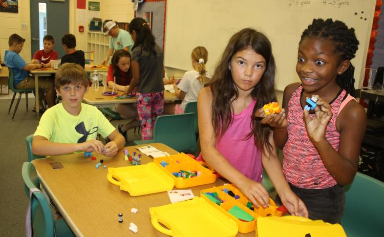 Columbia City Elementary students Jasom Chase (from left), Johanna Angelo and Cache Sheppard play with a set of Legos Wednesday morning. (TONY BRITT/Lake City Reporter)