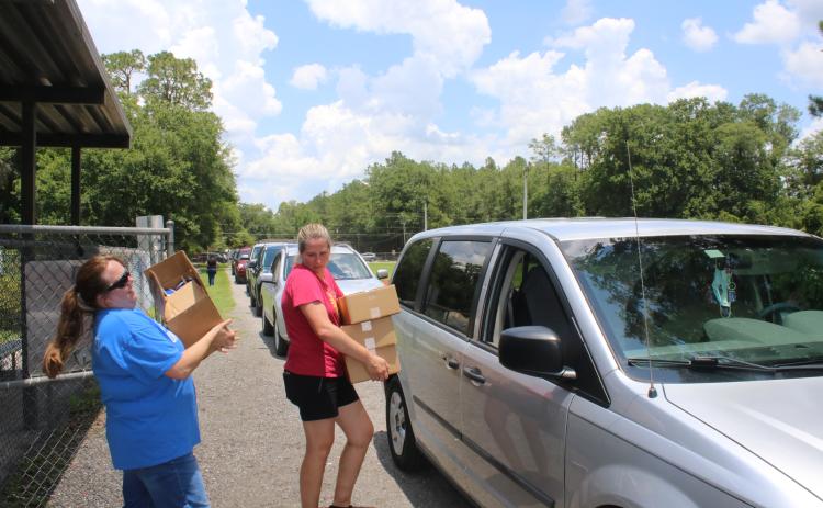 Alicia Blackford (left) and Laurie Renegar carry meals to a minivan Thursday afternoon at Five Points Elementary School. (TONY BRITT/Lake City Reporter)