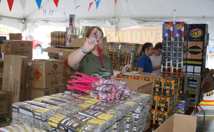 Kaleigh Clements, a Lake City Middle School student, arranges packs of bottle rockets Thursday at the CHS FFA Chapter TNT fireworks tent. Proceeds raised from the sales will be used to help fund the CHS FFA program. (TONY BRITT/Lake City Reporter)