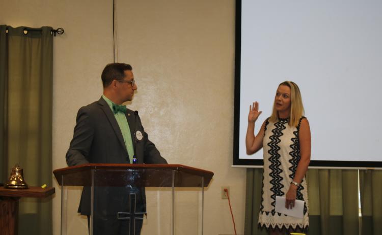 Lee Pinchouck (left), Rotary Club of Lake City immediate past president, reads the oath installing Meagan Logan as the club’s first female president Thursday. (TONY BRITT/Lake City Reporter)