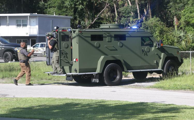 Law enforcement officers gather outside a building at the intersection of SW Main Boulevard and SW Ivan St. Monday afternoon after a man barricaded himself inside. (MORGAN MCMULLEN/Lake City Reporter)