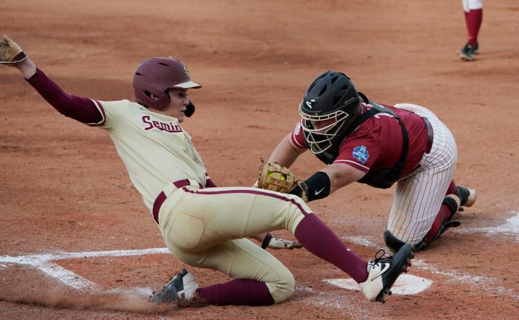 Florida State’s Dani Morgan, left, slides home safely as Alabama catcher Bailey Hemphill reaches in for the tag in the third inning of Monday’s Women’s College World Series semifinal game in Oklahoma City. (SUE OGROCKI/Associated Press)
