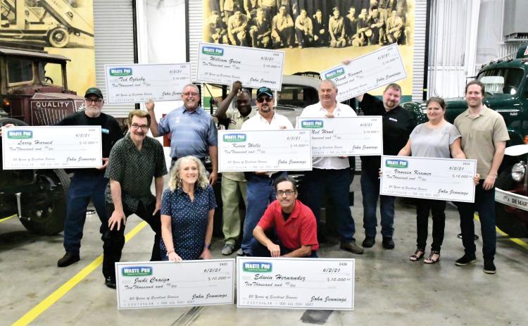 Nine Waste Pro employees were surprised recently with a $10,000 bonus for 20 years of service to the company, which was founded 20 years ago in Central Florida. Employees honored included, in front, Judi Craigo (from left) and Edwin Hernandez; in back, Larry Harned, Executive Board Chairman and founder John Jennings, Ted Oglesby, William Green, Kevin Wells, Neil Wood, Frank Kramer, Vanessa Kramer and Sean Jennings. (COURTESY)