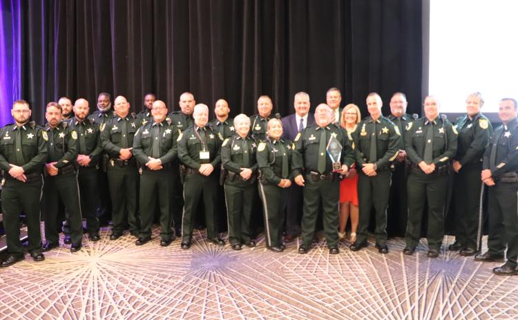 Sergeant Tim Ball (holding trophy) is joined by the 19 officers that make up the CCSO School Resource Unit Monday at the annual Florida Association of School Resource Officers conference. (COURTESY)