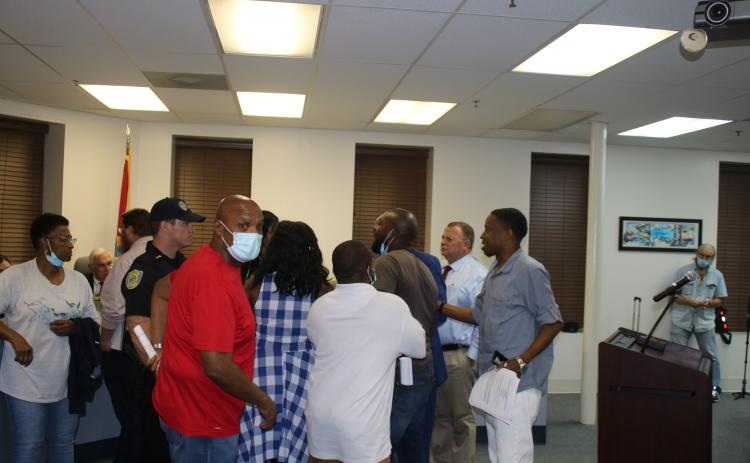 Conrad Wallace (foreground) and others attempt to restrain Sylvester Warren as he engages in a verbal confrontation with council member Eugene Jefferson. (TONY BRITT/Lake City Reporter)