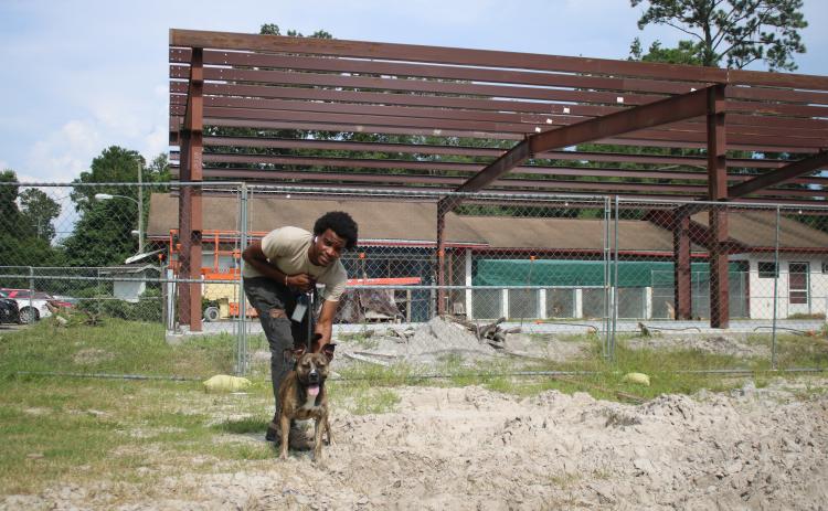 Jakwon Rhodes, a Lake City Humane Society employee, walks “Gunner” on the humane society campus Wednesday afternoon in front of the James Montgomery Animal Wellness Center Building, which has been under construction for weeks. (TONY BRITT/Lake City Reporter)