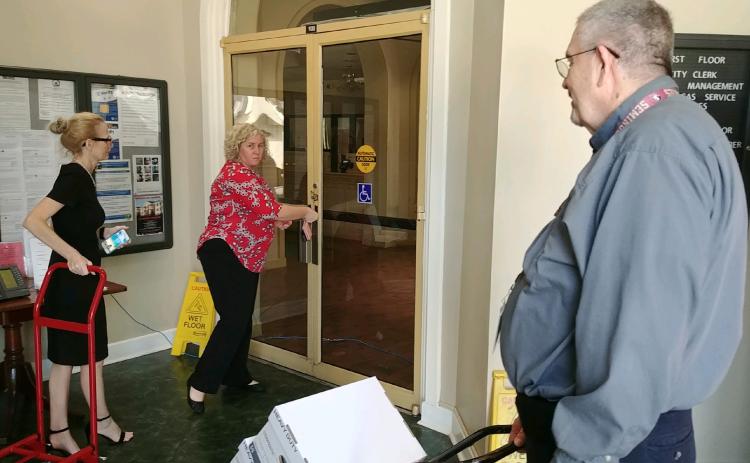 City Clerk Audrey Sikes (from left) and Records Coordinator Nikki Starling talk to Growth Management Director David Young as the three move boxes to their new temporary offices after mold was found on the first floor at city hall. (TONY BRITT/Lake City Reporter)