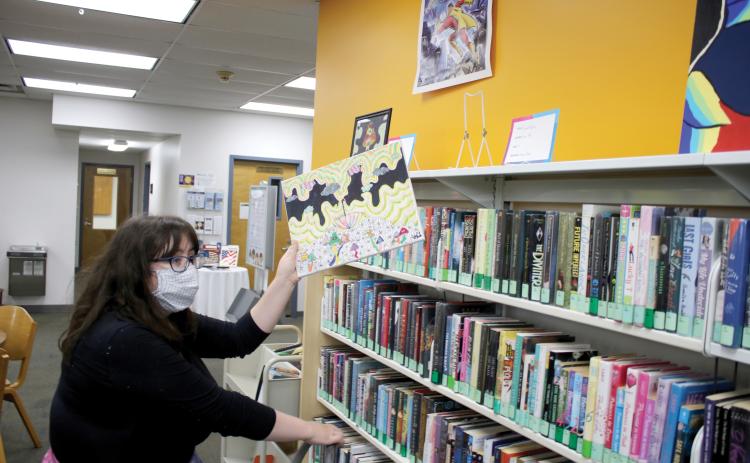 Columbia County Public Library Programming Specialist Emma Miles looks for a spot to display a piece of art. So far, 17 works have been submitted to this year’s Youth Art Contest. (TONY BRITT/Lake City Reporter)