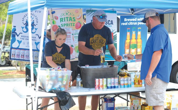 A pair of craft beer vendors deliver service to an attendee of the 2019 Gateway City Craft Beer & Wine Festival. (FILE)
